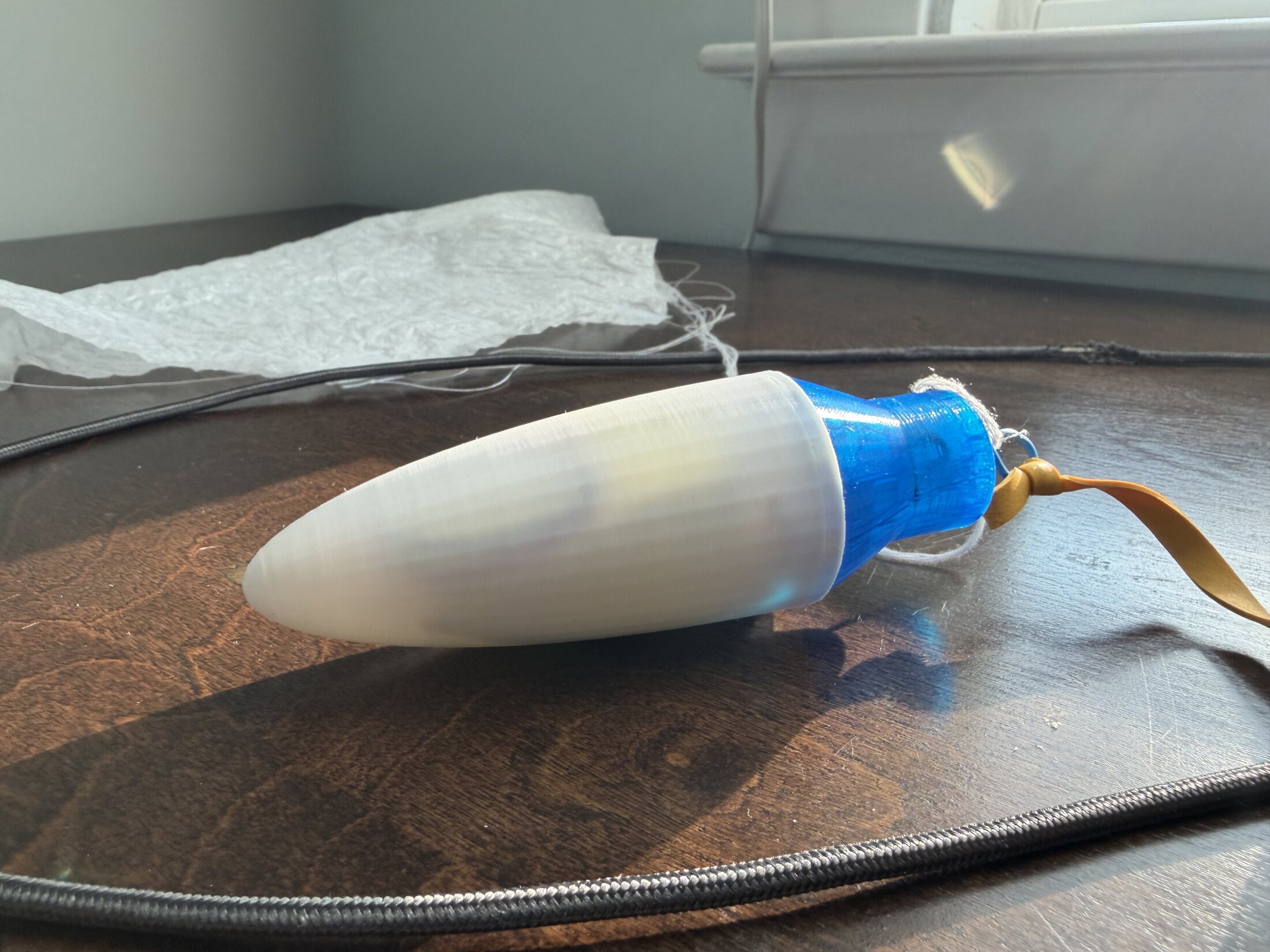 Nose cone assembled onto blue adapter with parachute behind